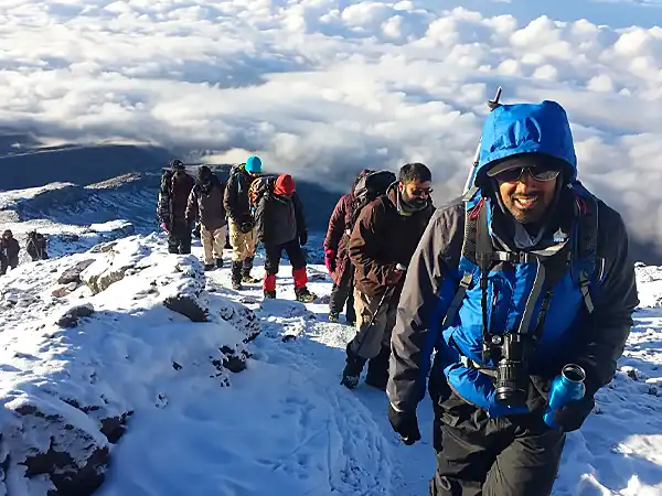 Smiling climbers in warm jackets on a snowy Kilimanjaro trail