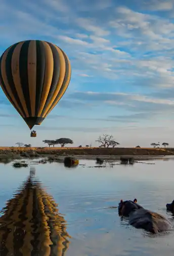 A hot air balloon reflected in still water at dawn
